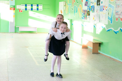 Full length of girl carrying friend on back at school