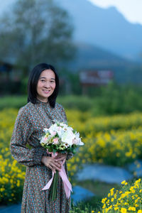 Portrait of smiling young woman standing on field