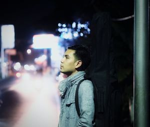 Thoughtful man standing at illuminated city street during night