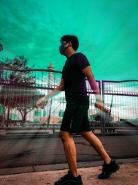 Side view of young man standing on footpath