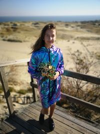Portrait of girl holding bouquet while standing at beach