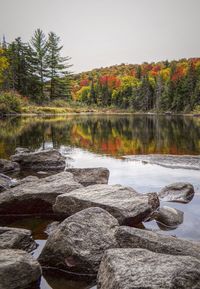 Rocks by lake against sky during autumn