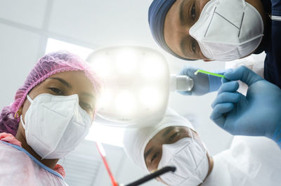 Low angle portrait of surgeons wearing mask standing in operating room