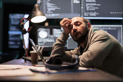 Young man using mobile phone at desk in office