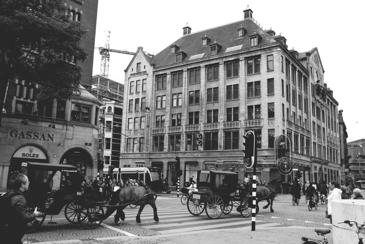 building exterior, architecture, built structure, men, street, city, person, large group of people, lifestyles, city life, building, walking, window, transportation, city street, leisure activity, land vehicle, day, residential building