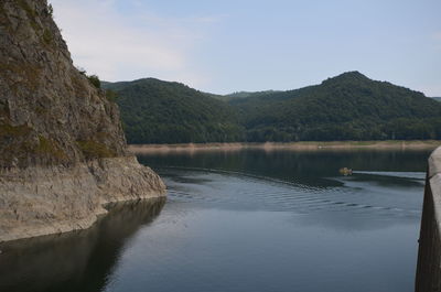 Scenic view of lake by mountains against sky