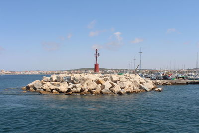Lighthouse by sea against sky