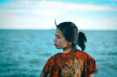 Young woman looking at sea against sky