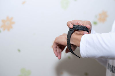 Close-up of man hand wearing wristwatch against white wall