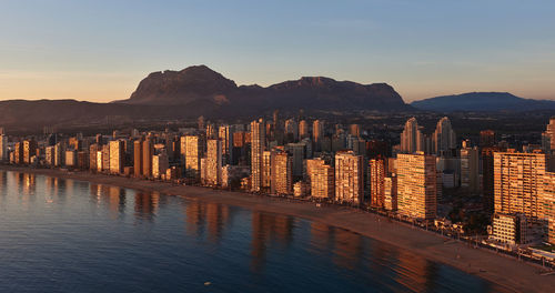 Panoramic view of city by sea against sky during sunset