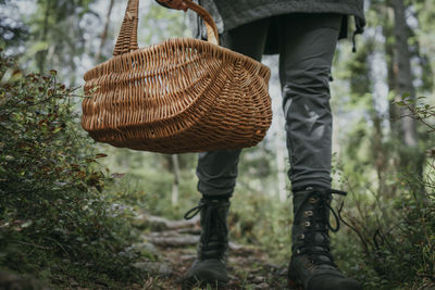 Low section of woman carrying wicker basket