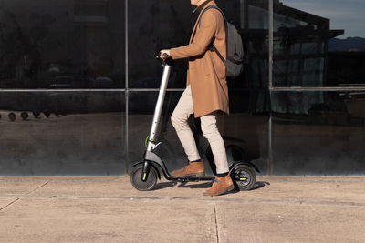 Unrecognizable businessman on daily commute riding micro scooter 