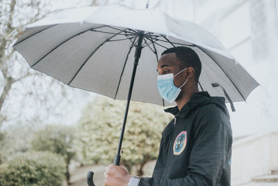 Man holding umbrella standing on rainy day