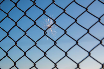 Full frame shot of chainlink fence against blue sky