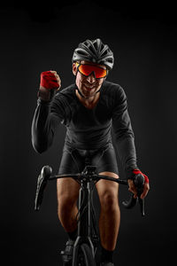 Low angle view of man riding bicycle against black background