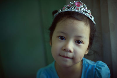 Portrait of girl wearing crown while sitting at home