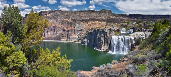 Scenic view of waterfall in forest against sky