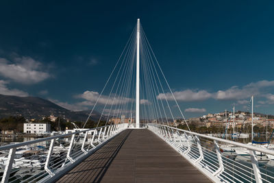 Low angle view of suspension bridge against cloudy sky