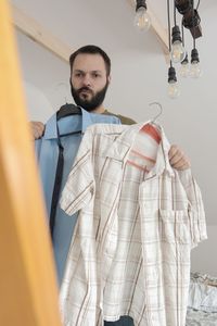 Portrait of young man standing at home and changing shirt