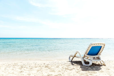 Lone white blue sun lounger stands on seashore next to water. beach holiday by the sea or ocean.