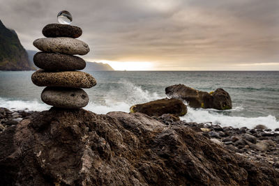 Rocks on beach against sky during sunset