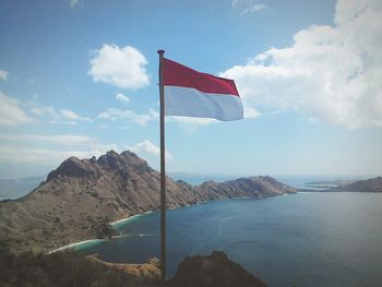 Indonesian flag waving on cliff with sea in background against blue sky