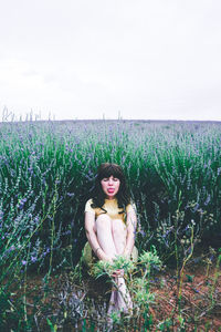 Portrait of young woman on field against sky