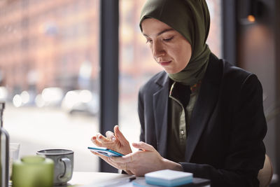 Woman using cell phone in cafe