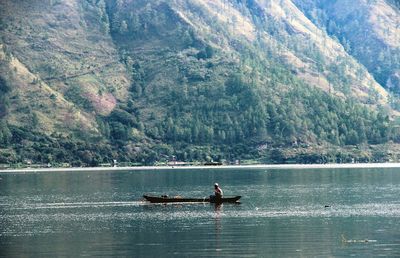 People in boat on lake against mountain