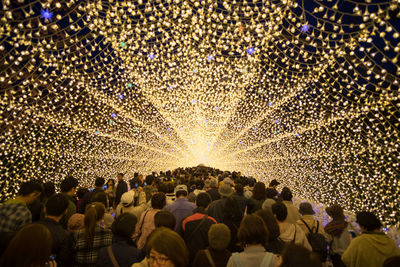 Crowd standing in illuminated walkway at night