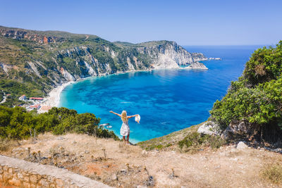 Rear view of person by sea against blue sky