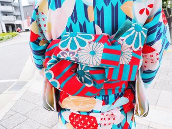 Low section of woman holding multi colored umbrella