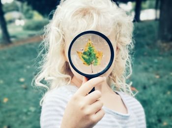 Girl holding magnifying glass with maple leaf