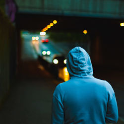 Rear view of man standing on illuminated street at night