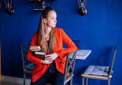 A young woman holds a stack of books. teaching a student according to textbooks.