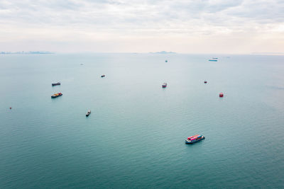 Aerial seascape view and small container ship floating in sea horizon and cloud sky background 