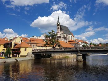Bridge over river by buildings against sky in city