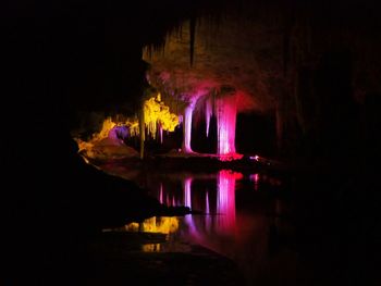 Illuminated cave in water at night