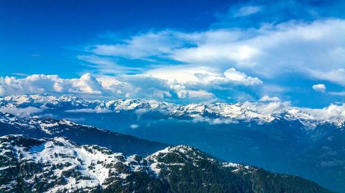 Scenic view of snow covered mountains against blue sky