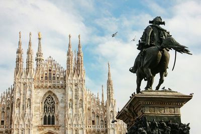 Statue in city against sky