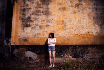 Full length of woman standing against wall