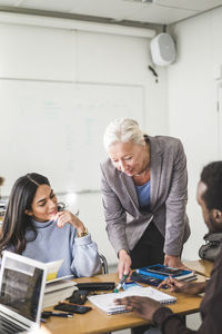 Mature female teacher explaining students in classroom