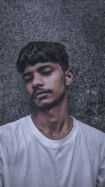Portrait of young man standing against wall