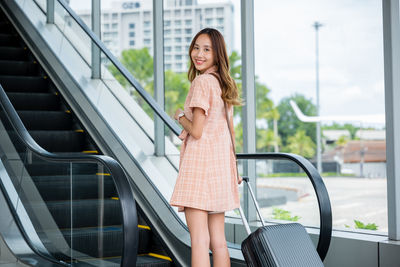 Portrait of young woman sitting on escalator
