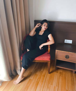 Portrait of young woman sitting on hardwood floor