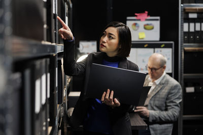 Portrait of woman using laptop while sitting in office