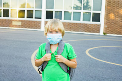 Kid in mask during corona virus outbreak. little child  in mask carrying backpack, going to school.