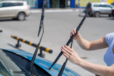 Cropped hand holding umbrella on street in city