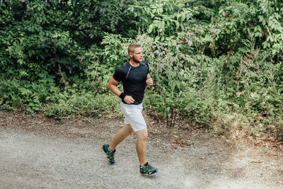 Full length of young man running in forest