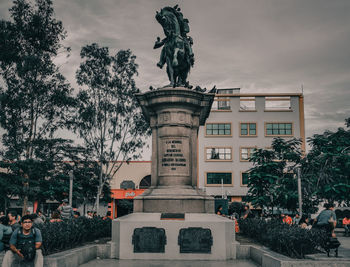 Statue in city against cloudy sky